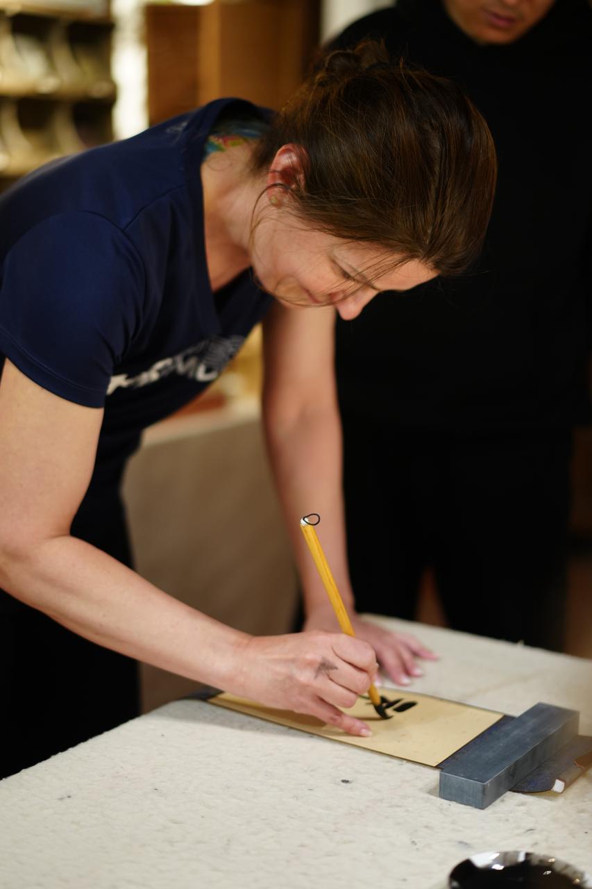 Traveler trying Chinese calligraphy with ink brush
